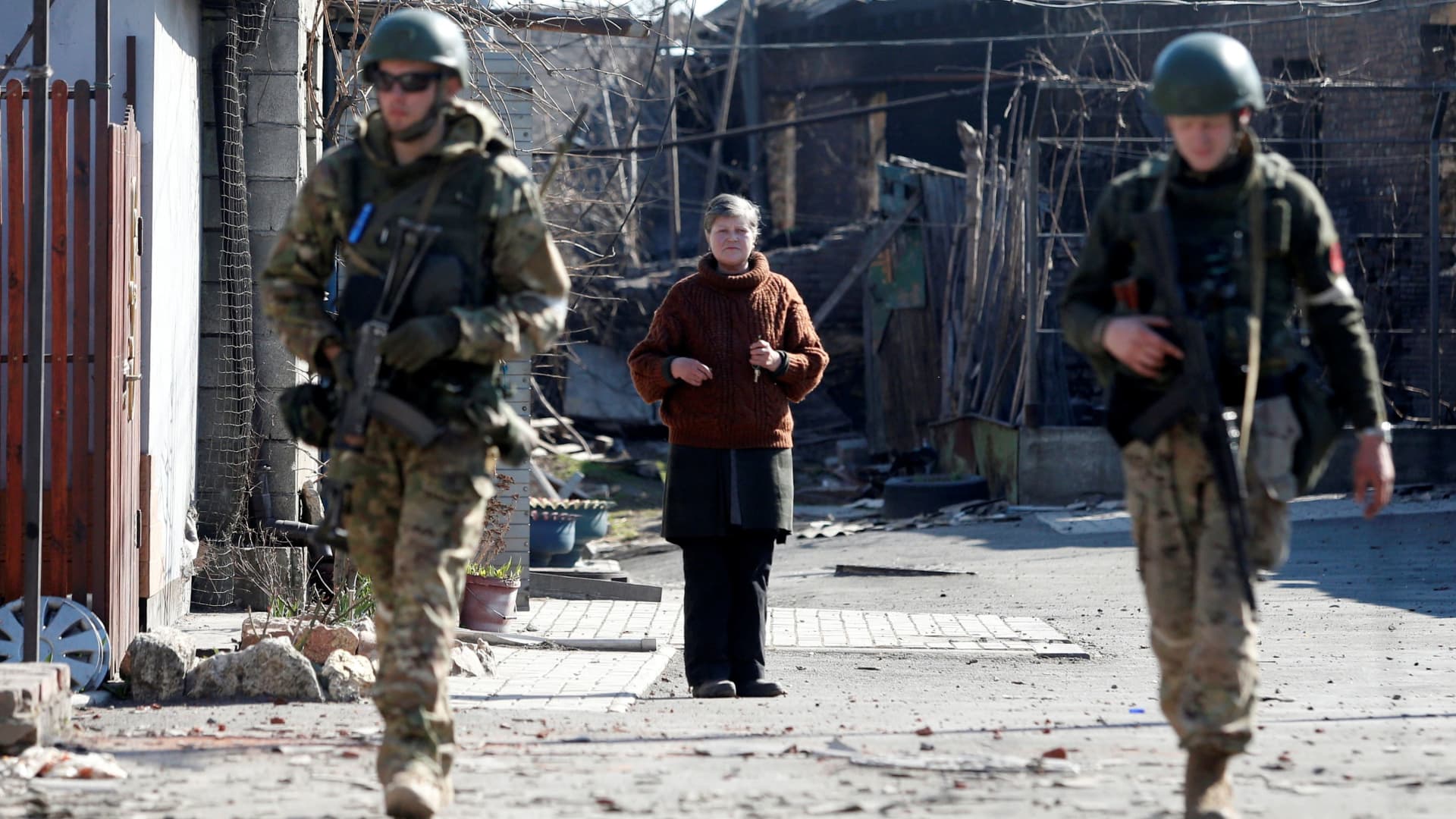 A local resident looks on as service members of pro-Russian troops inspect streets during Ukraine-Russia conflict in the southern port city of Mariupol, Ukraine April 7, 2022.