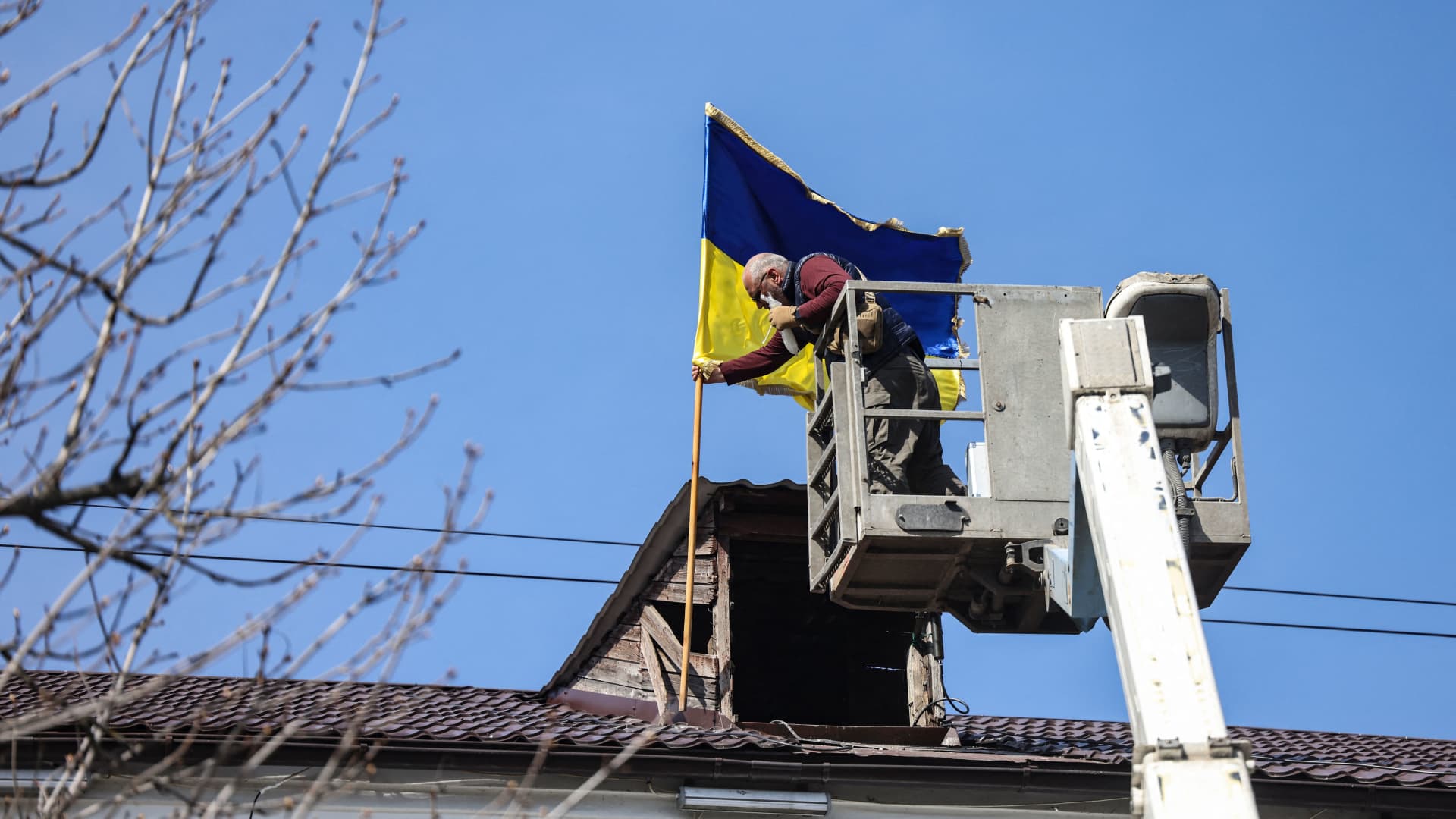 An employee rises the Ukrainian flag at the city hall of Bucha, western Kiev, on April 7, 2022.