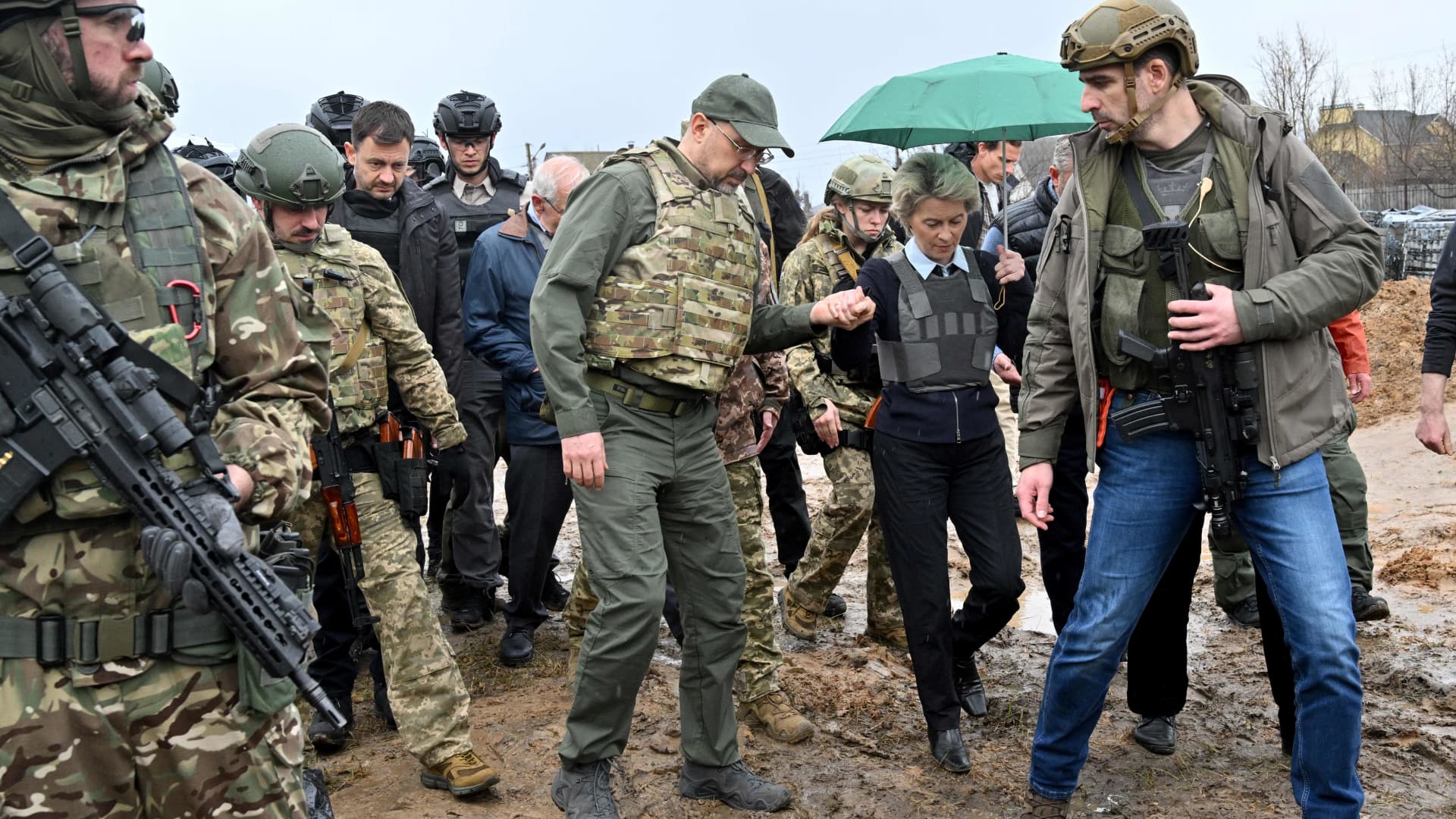 Ukrainian Prime Minister Denys Shmyhal helps European Commission President Ursula von der Leyen across the mud during a visit with Slovakia's Prime Minister and European Union High Representative for Foreign Affairs and Security Policy to a mass grave in the town of Bucha, northwest of Kyiv on April 8, 2022.