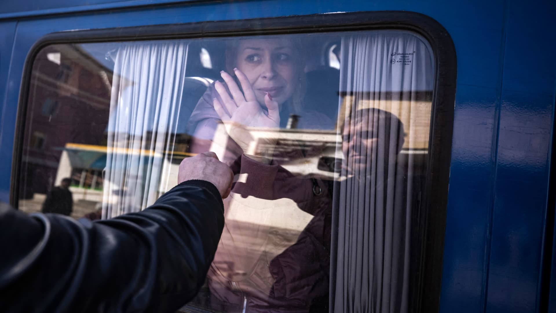 A woman waves to say good bye to her husband as she leaves on a bus, a day after a rocket attack at a train station in Kramatorsk, on April 9, 2022.