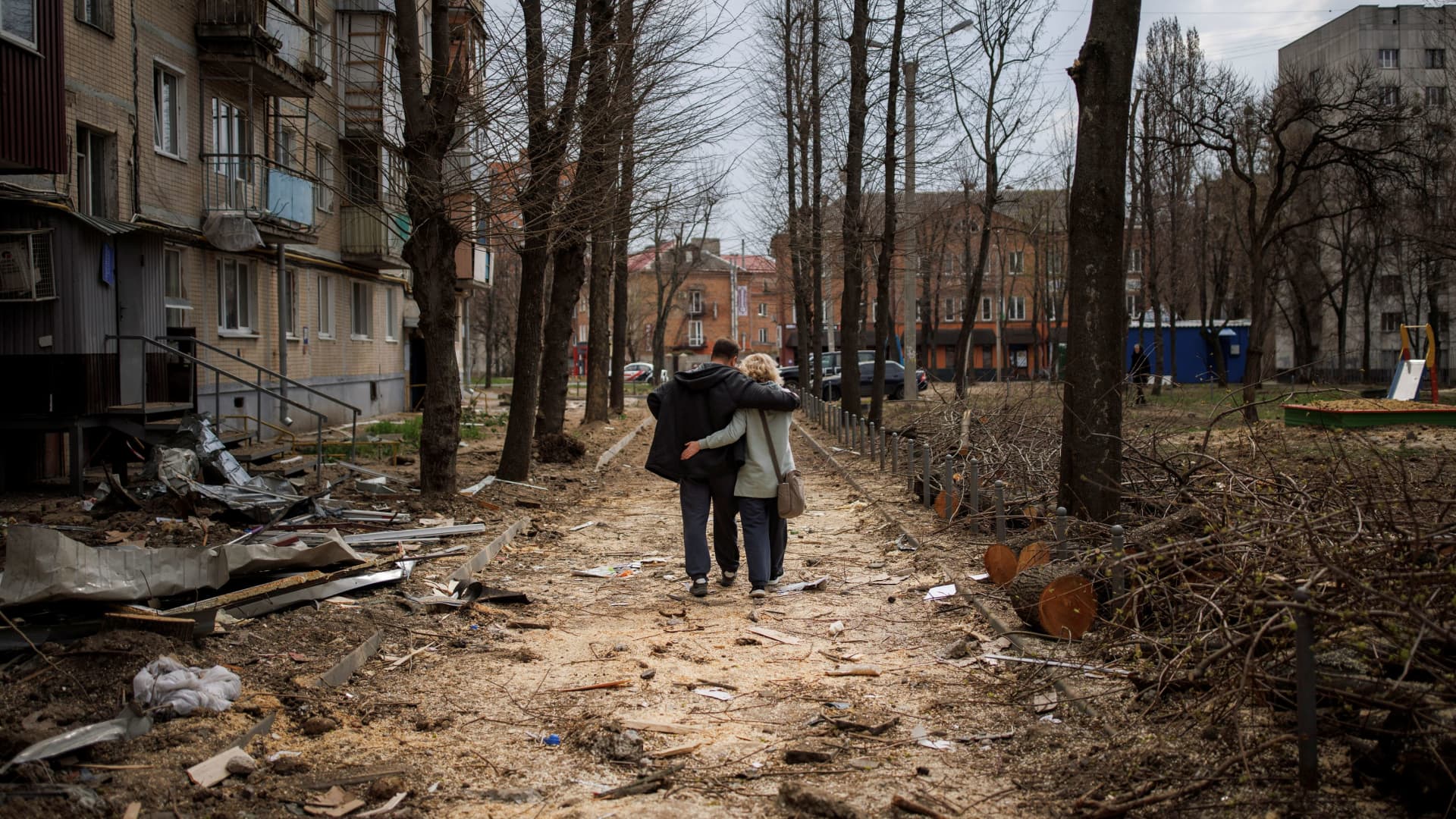 A couple hugs while walking past a building that was heavily damaged by shelling, as Russia's attack on Ukraine continues, in Kharkiv, Ukraine, April 10, 2022. 