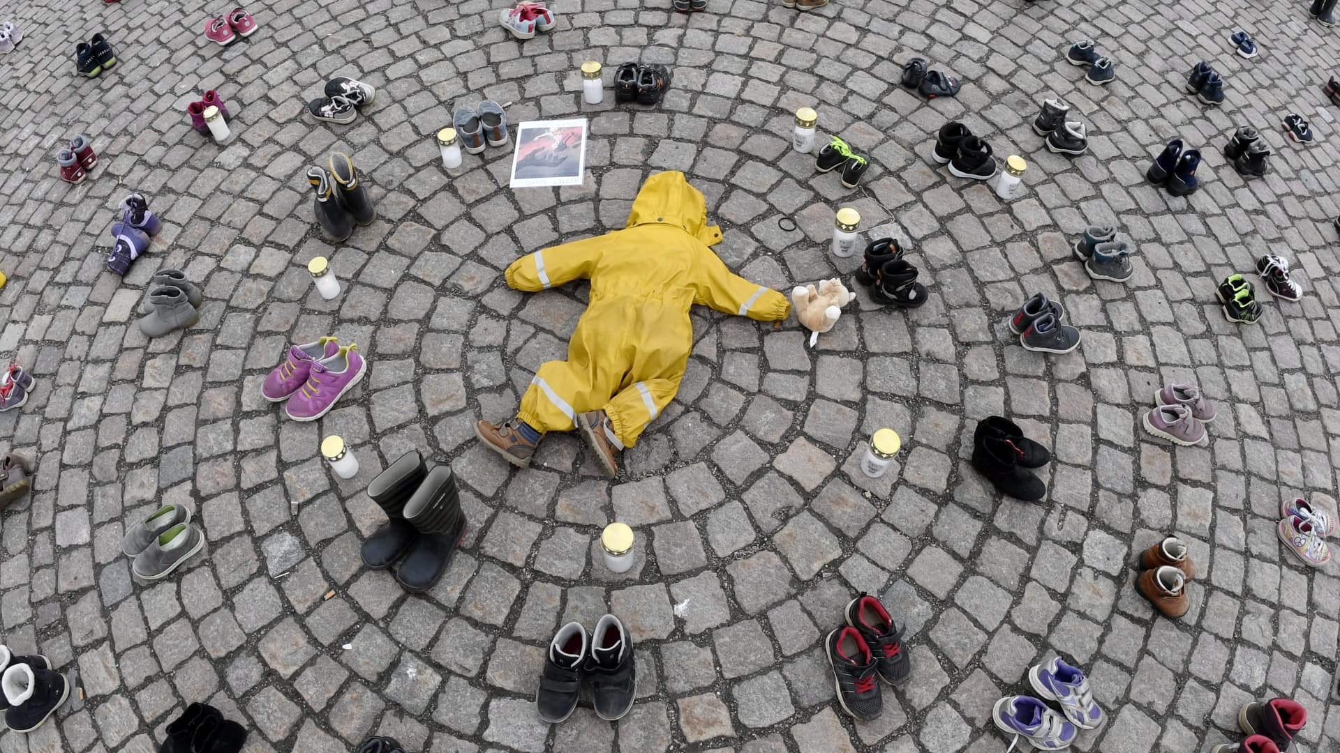 Candles, a children's clothing and shoes are seen during a demonstration organized by the Ukrainian Association in Finland, to honor the memory of the children killed in Mariupol, Ukraine, in Helsinki, on April 10, 2022.