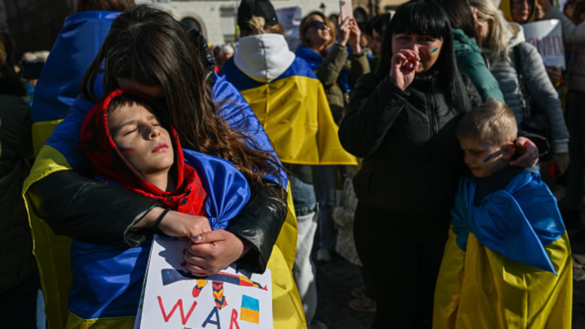 A Ukrainian mother draped in the national flag hugs her son during a peaceful protest against the killing of children by the Russian army during the invasion of Ukraine on April 10, 2022, in Krakow, Poland.