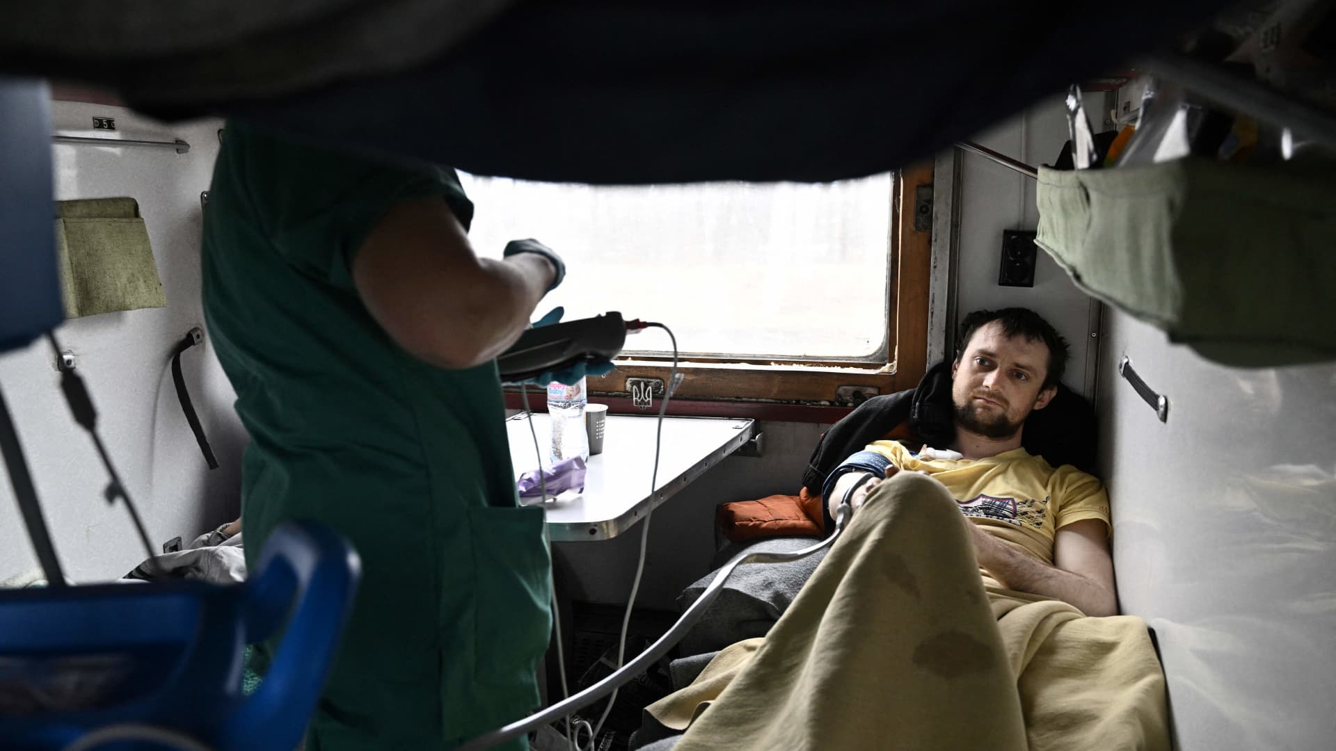 An MSF nurse cares for Evhen Perepelytsia (R), a patient on a medical evacuation train on its way to the western Ukrainian city of Lviv on April 10, 2022