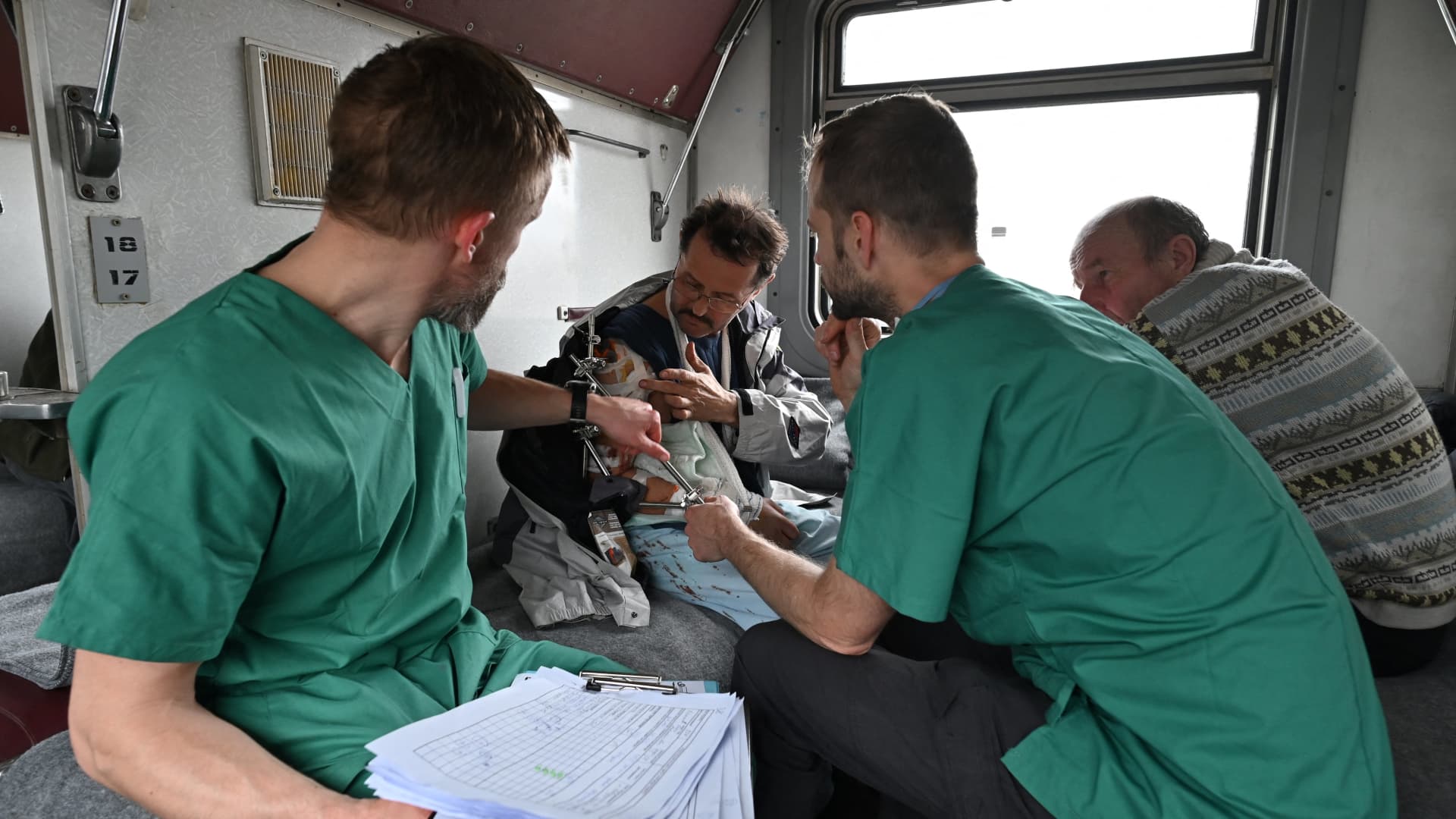 MSF doctors Stig Walravens (2nd R), 33, and Yaroslav (L), 39, care for Oleh, 58, a patient on a medical evacuation train on its way to the western Ukrainian city of Lviv on April 10, 2022.
