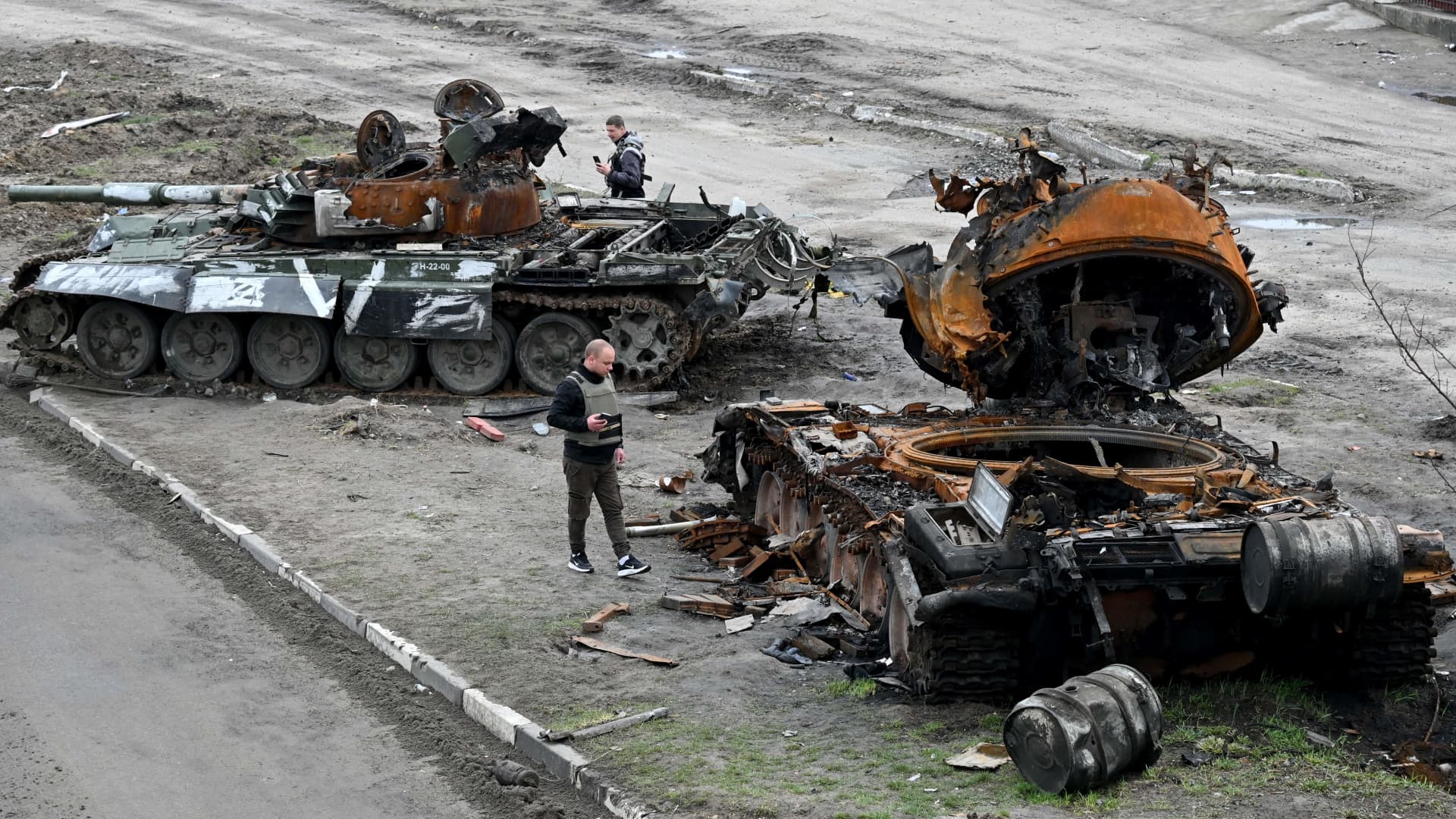 Residents look at a destroyed Russian tank on the outskirts of Buzova village, west of Kyiv, on April 10, 2020.