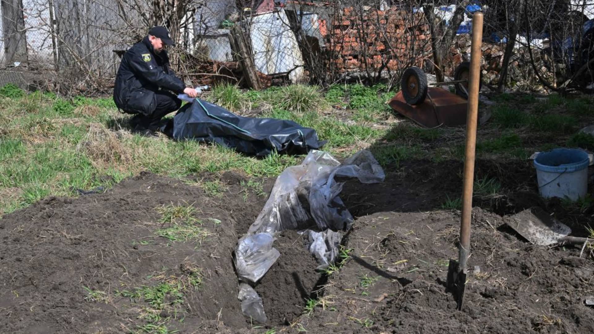 EDITORS NOTE: Graphic content / A policeman attends to the body of a civilian man buried in the yard of his house after his was exhumed in Andriivka village, Kyiv region, on April 11, 2022.