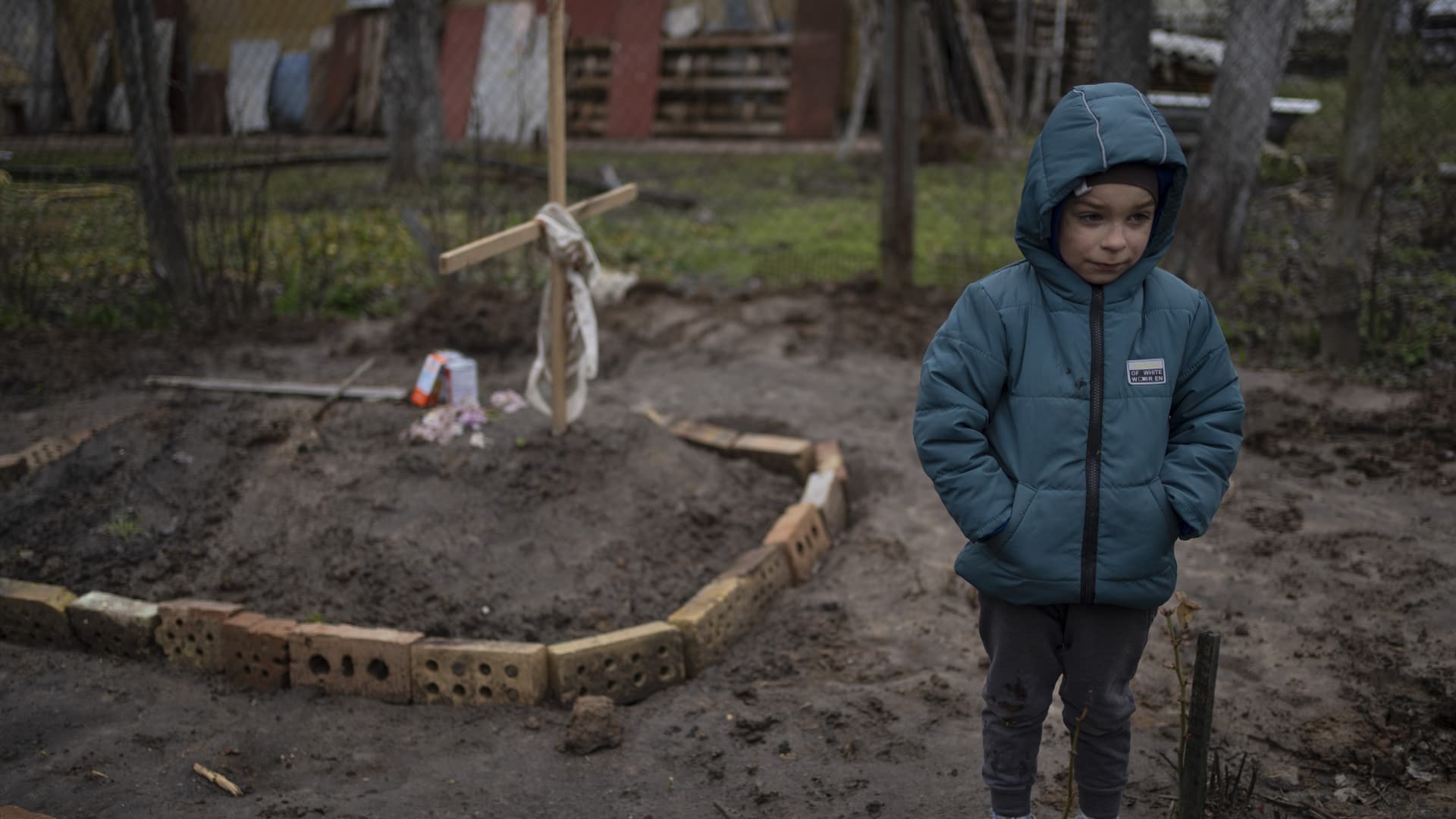 In the courtyard of their house, Vlad, 6, stands near the grave of his mother, who died, on the outskirts of Kyiv, Ukraine, Monday, April 4, 2022.