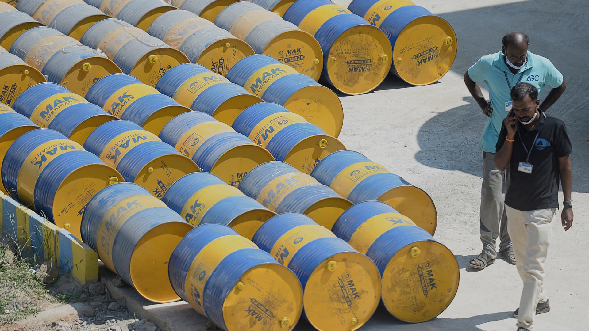 Workers walk past oil barrels at a filling station in n Chennai on February 24, 2022.