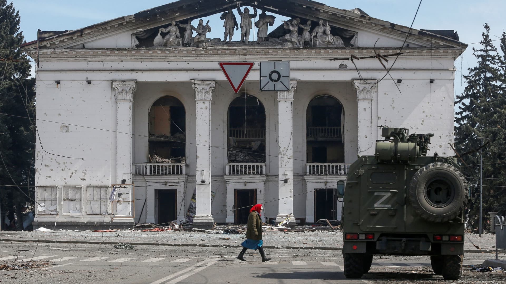 A woman walks next to an armoured vehicle of pro-Russian troops the building of a theatre destroyed in the course of Ukraine-Russia conflict in the southern port city of Mariupol, Ukraine April 10, 2022. 