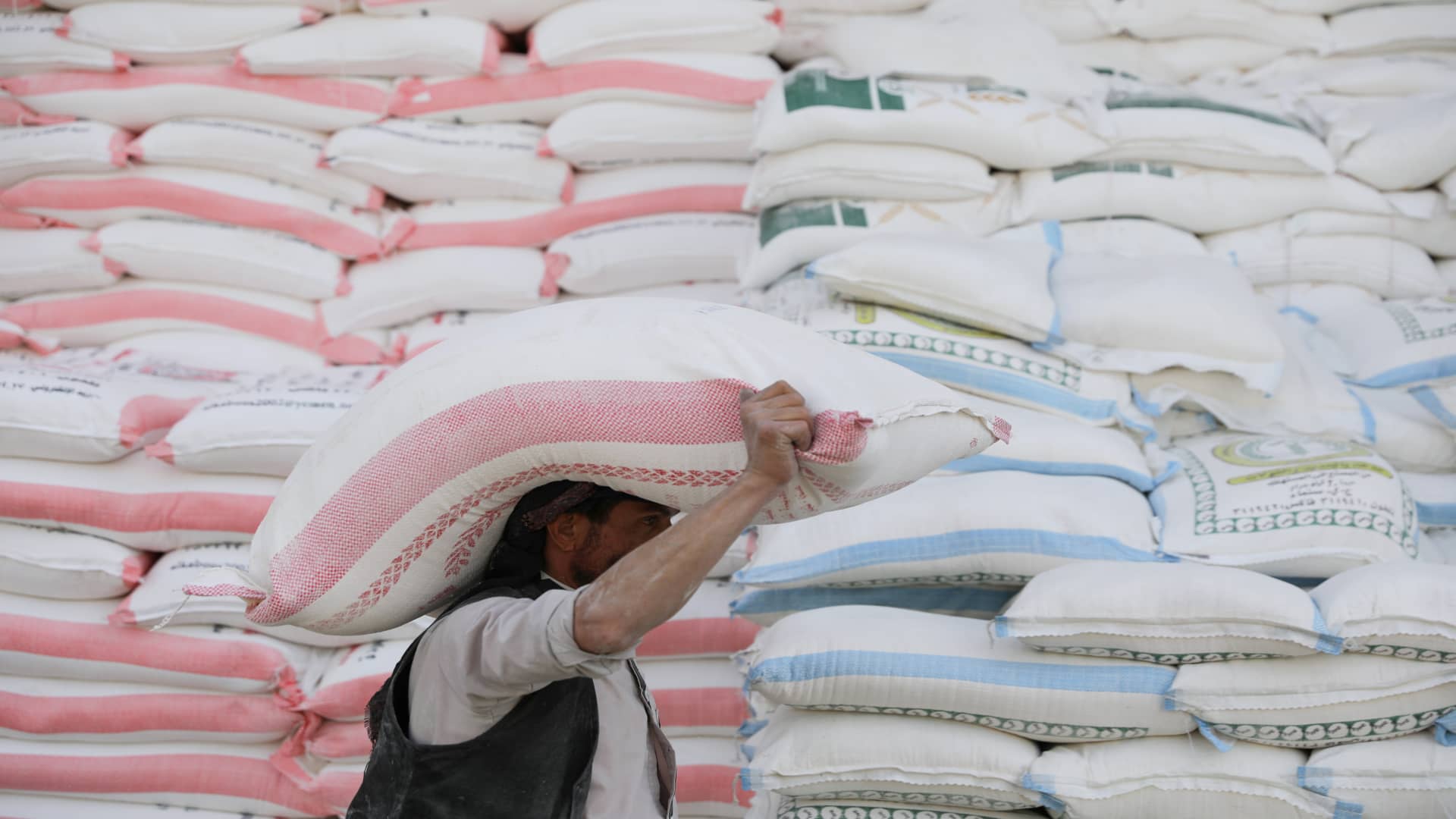 A worker carries a sack of wheat flour outside a wholesale food shop in Sanaa, Yemen February 28, 2022. 