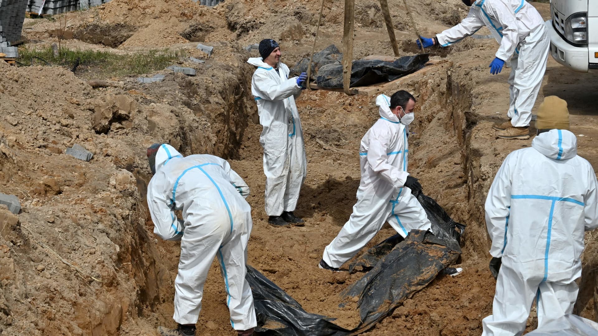 Workers exhume bodies from a mass grave in Bucha, north-west of Kyiv, on April 14, 2022.
