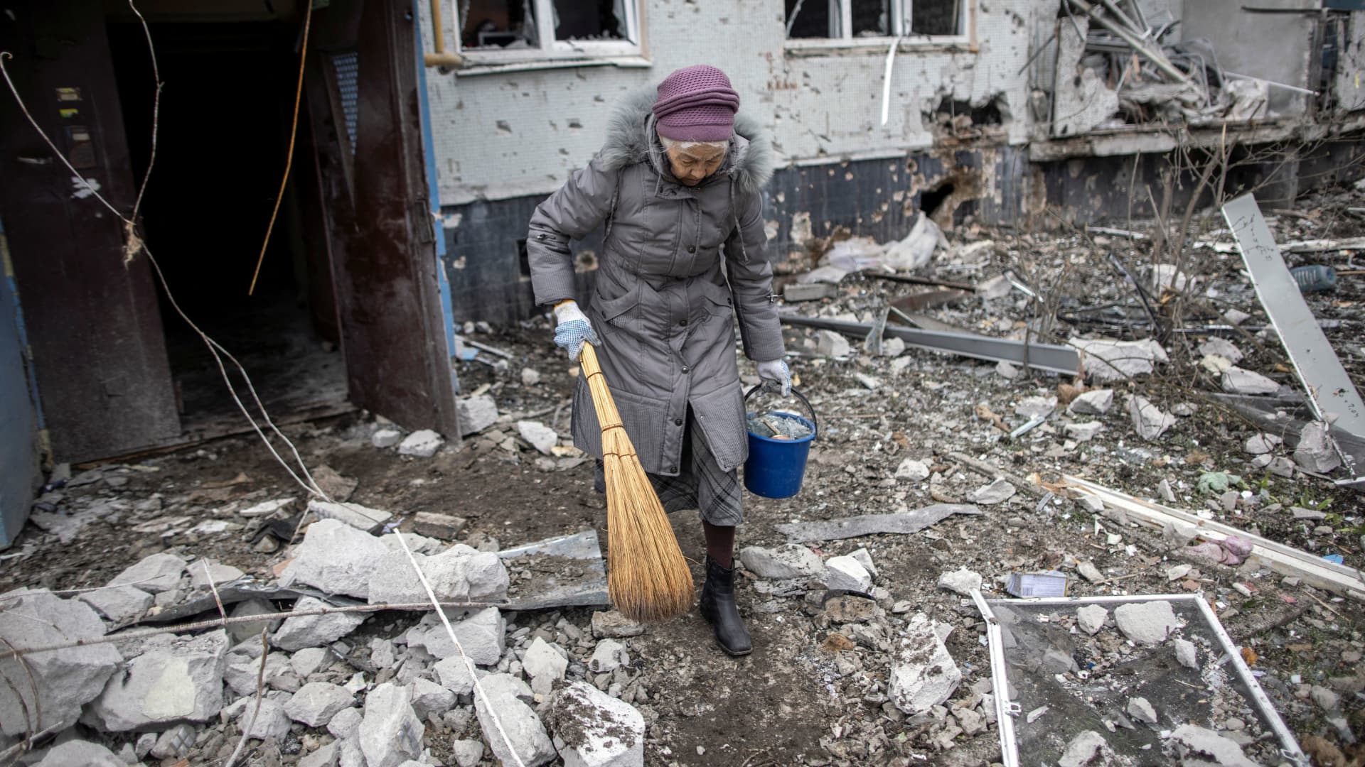 A woman holds a broom outside a heavily damaged apartment block, following an artillery attack, amid Russia's attack on Ukraine, in Kharkiv, Ukraine, April 13, 2022. 