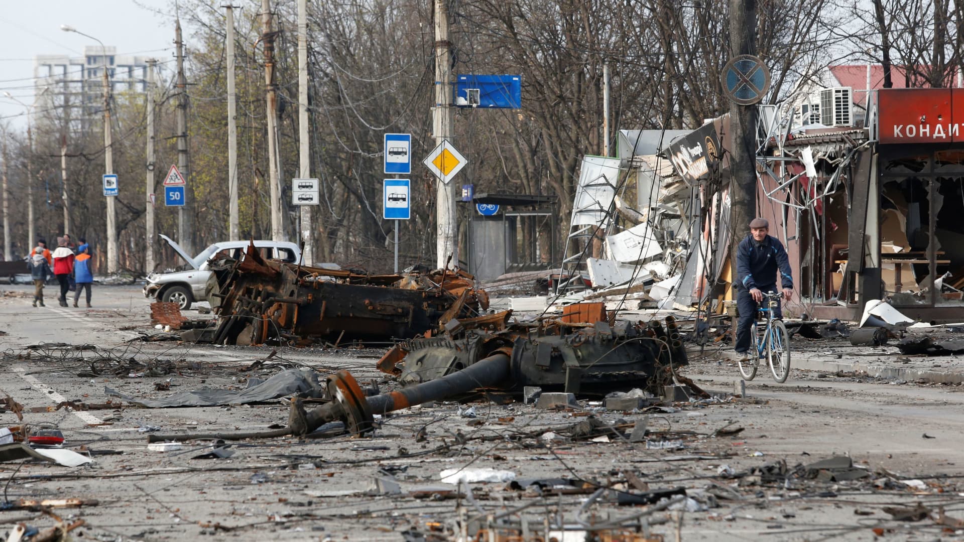 A man rides a bicycle near a destroyed tank during Ukraine-Russia conflict in the southern port city of Mariupol, Ukraine, on April 17, 2022.
