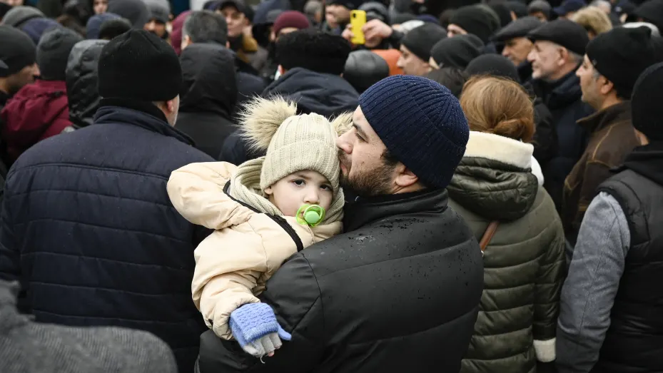 A man holds his child as families, who fled Ukraine due to the Russian invasion, wait to enter a refugee camp in the Moldovan capital Chisinau on March 3, 2022.
