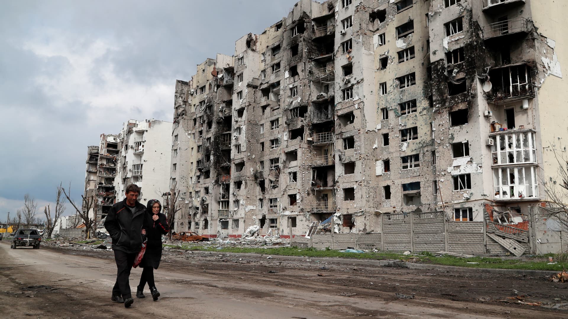 People walk along a street near residential buildings destroyed during Ukraine-Russia conflict in the southern port city of Mariupol, Ukraine April 22, 2022.