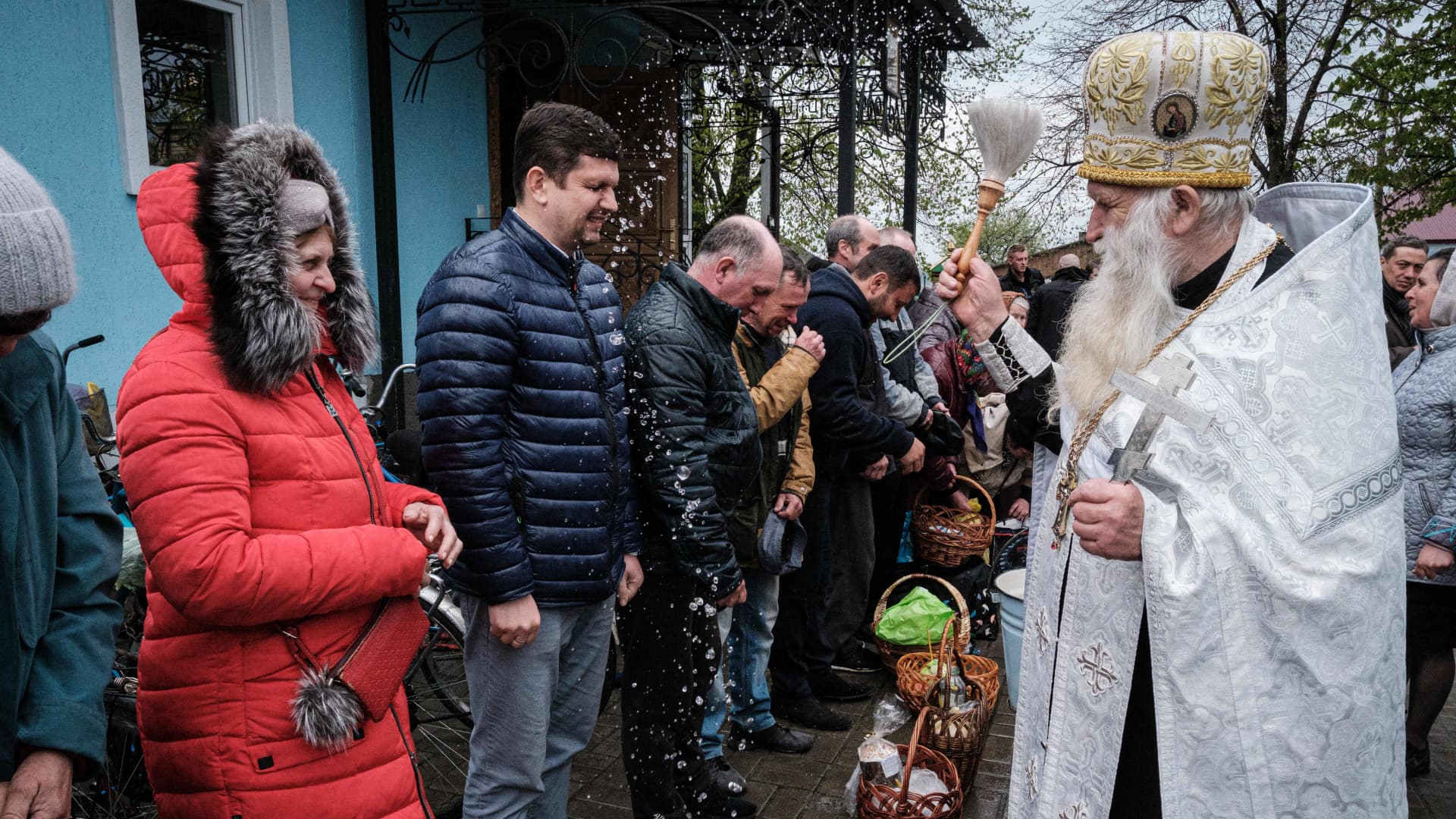 Worshippers receive a sanctification during an Orthodox Easter service with continuous sounds of shelling in the distance at St. Peter and Paul church in Lyman, eastern Ukraine, on April 24, 2022, amid the Russian invasion of Ukraine.