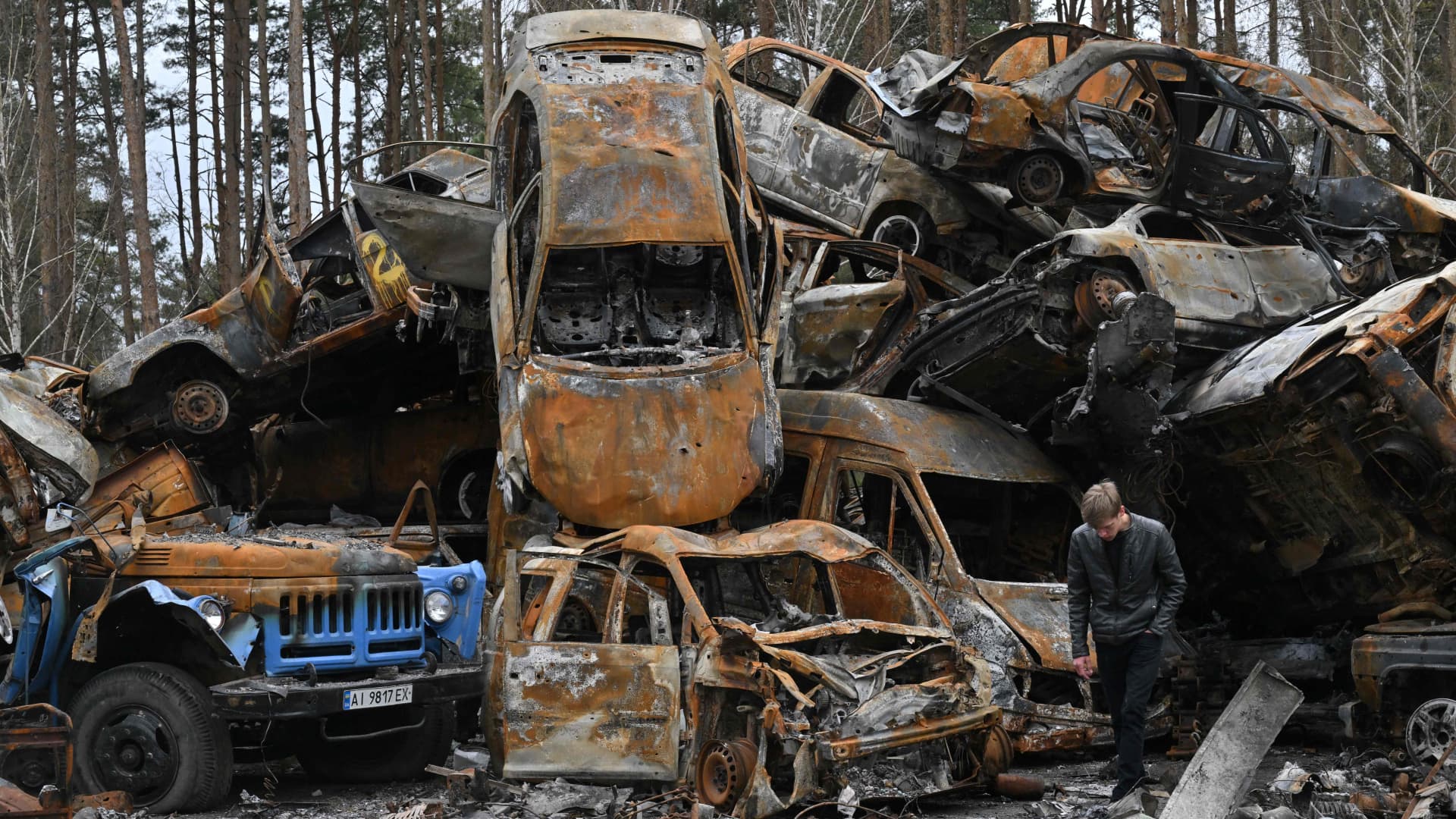 A man walks past destroyed and burned cars in Irpin on April 19, 2022, during the Russian invasion of Ukraine.