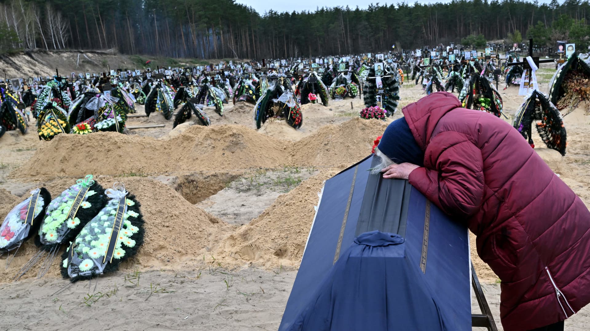 A woman reacts next to the coffin of her husband during a funeral at a cemetery in Irpin on April 19, 2022, where there are at least three rows of new graves for those killed during the Russian invasion of Ukraine.