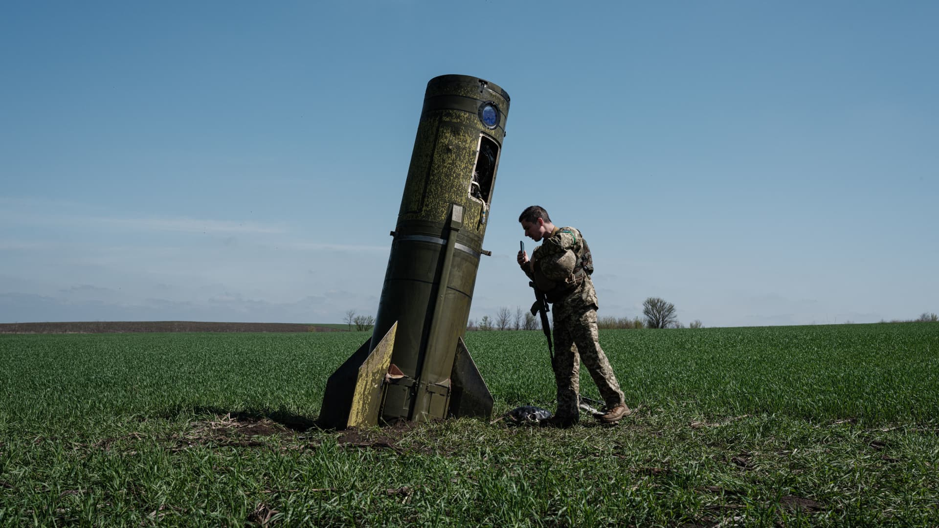 A Ukrainian serviceman looks at a Russian ballistic missile's booster stage that fell in a field in Bohodarove, eastern Ukraine, on April 25, 2022, amid the Russian invasion of Ukraine.