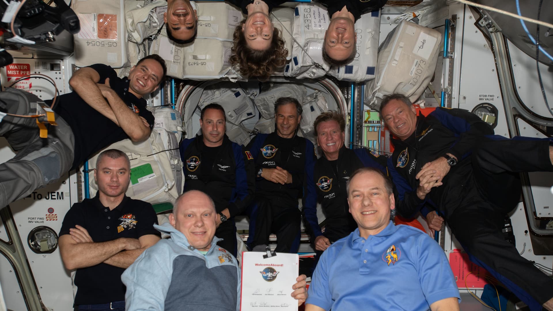 The four members of the Ax-1 crew – center, in black and blue flight suits – with the other seven astronauts of the International Space Station's Expedition 57 on
