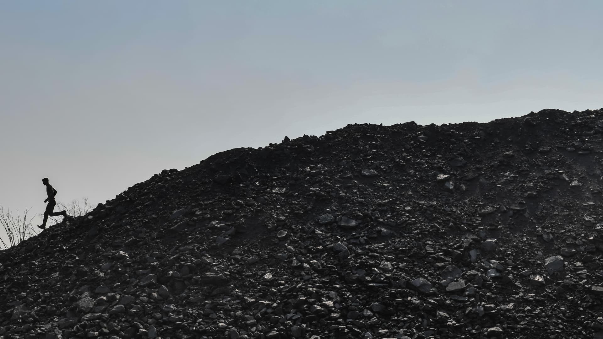 A worker walks atop a pile of coal at a coal yard near a mine on November 23, 2021 in India. Russian and Indian officials met last week hoping to resolve coking coal supply issues, a trade source and an Indian government source said, according to Reuters.