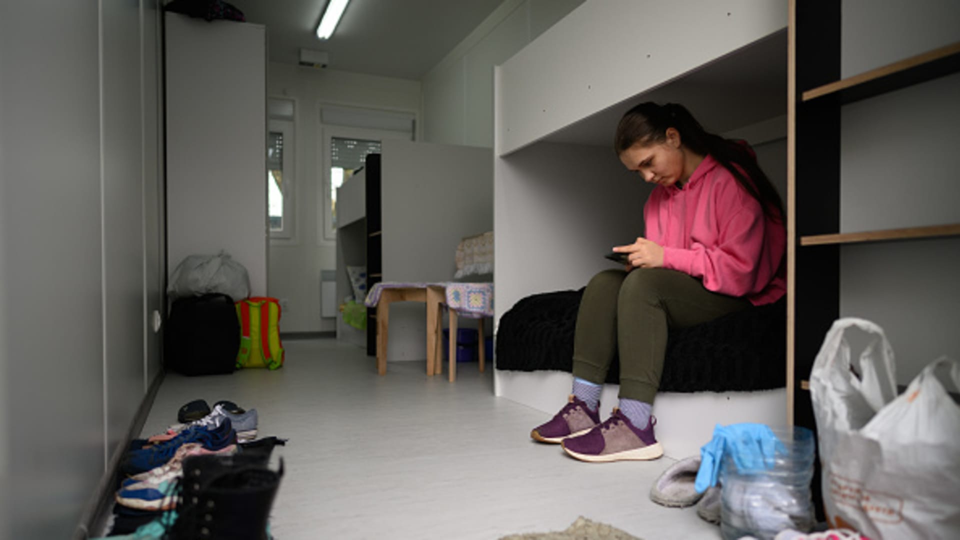 Albina Nagorna, aged 16, reads a book on her mobile phone in her family's temporary home in a converted shipping container on April 26, 2022 in Lviv, Ukraine.