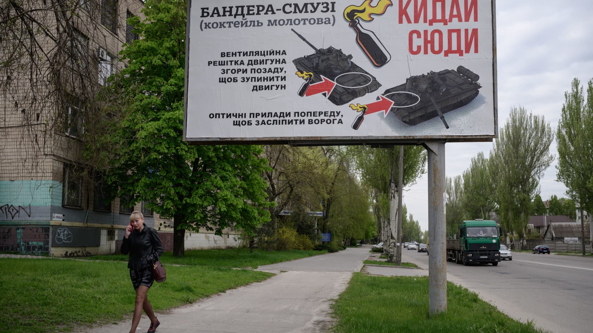 A woman walks past a billboard advising where to target tanks when throwing molotov cocktails, in Zaporizhzhia on April 29, 2022, on the 65th day of the Russian invasion of Ukraine.