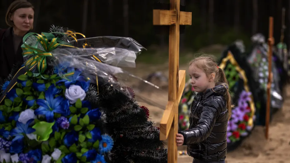 Darya Piven, 33, looks as her daughter Zlata, 6, as she visits the graves of her parents Nadiya Myakushko, 69, and Volodymyr Cherednichenko, 75, who were killed by Russian army in Irpin on March 24, in Irpin, on the outskirts of Kyiv, Monday, April 25, 2022.