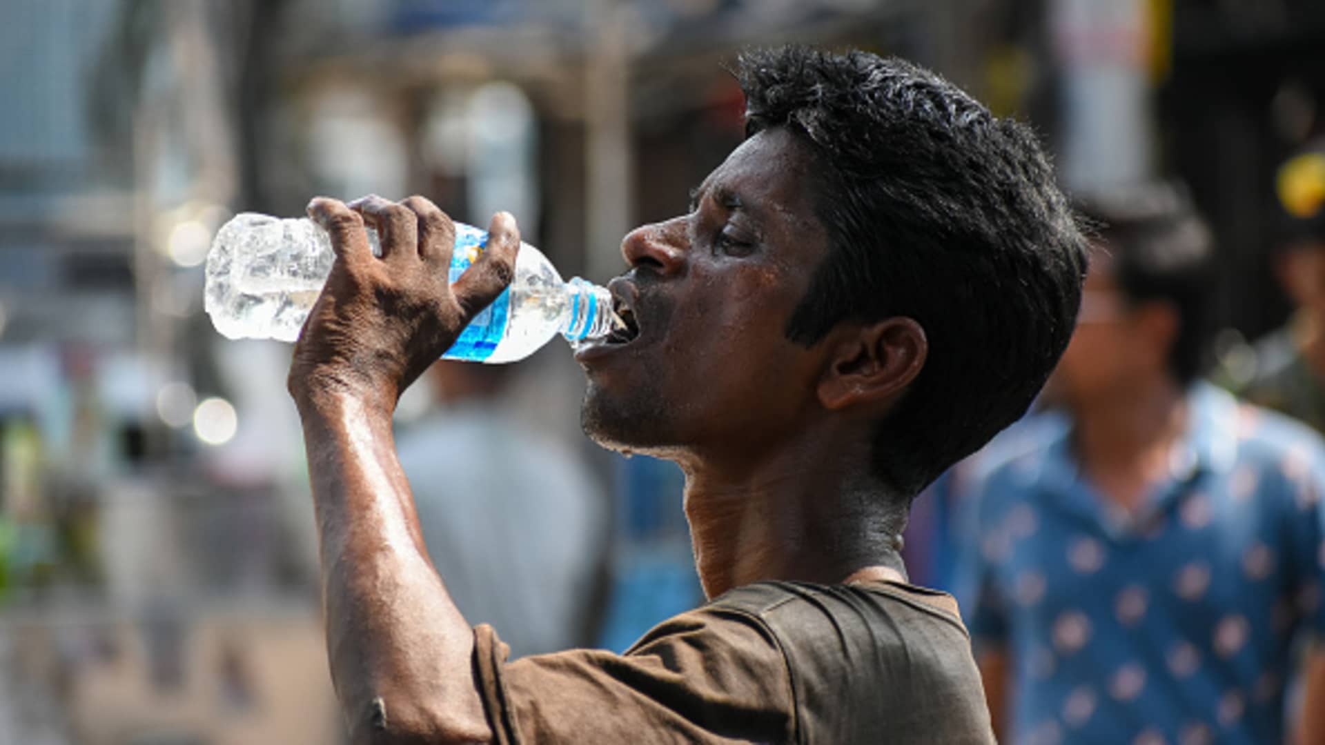 A man is seen drinking water to relieve himself of summer heat , at a street side in Kolkata, India, on 29 April 2022.