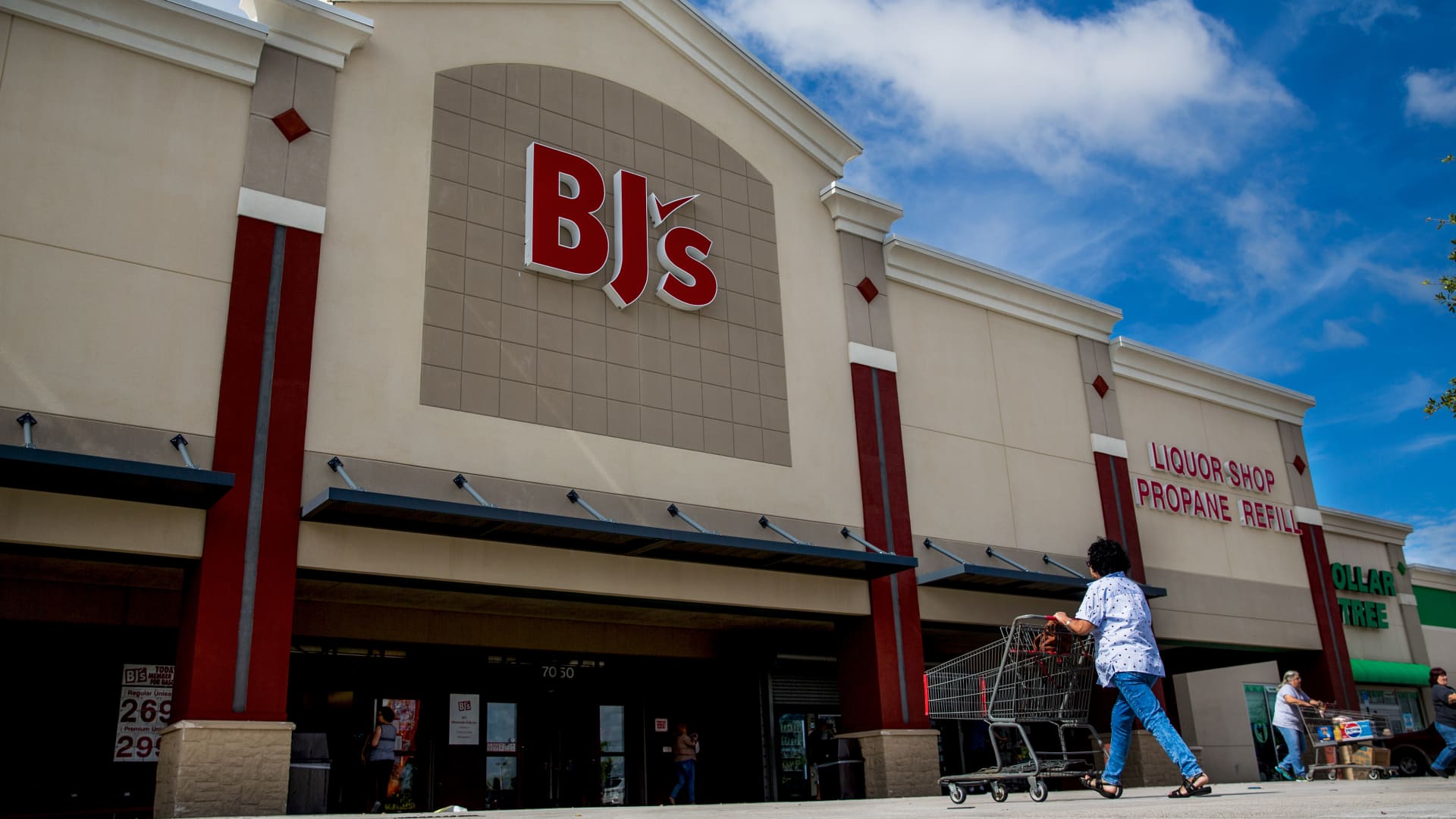 A customer pushes a shopping cart towards the entrance of a BJ's Wholesale Club Holdings Inc. location in Miami, Florida.