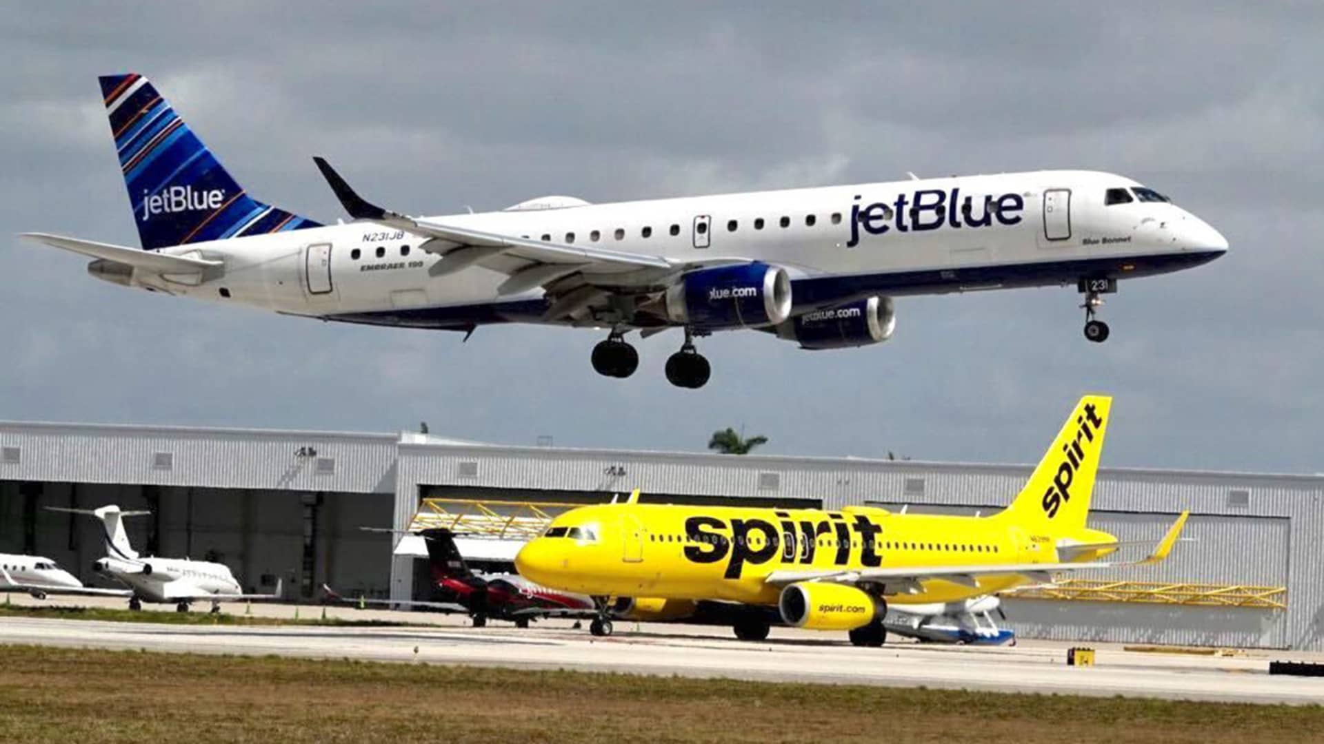 A JetBlue airliner lands past a Spirit Airlines jet on taxi way at Fort Lauderdale Hollywood International Airport on Monday, April 25, 2022. (Joe Cavaretta/Sun Sentinel/Tribune News Service via Getty Images)