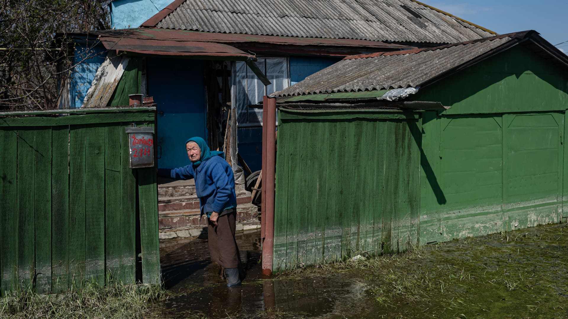 DEMYDIV, UKRAINE - MAY 02: Mariia, 82, stands on the entrance to her flooded household, on May 2, 2022 in Demydiv, Ukraine. To keep Russian armoured columns at bay, Ukrainian forces released water from a nearby hydroelectric dam to intentionally flood Demydiv, a village north of Kyiv. The decision was effective, but efforts to drain the area are complicated.(Photo by Alexey Furman/Getty Images)
