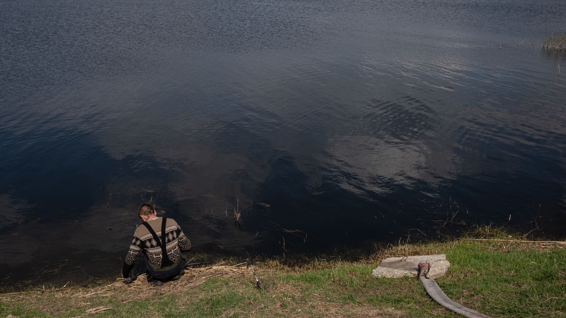 Oleksandr, 39, sits by the flooded field as he takes a smoking break after fixing the engine pumping out the water from the flooded areas, on May 2, 2022 in Demydiv, Ukraine.