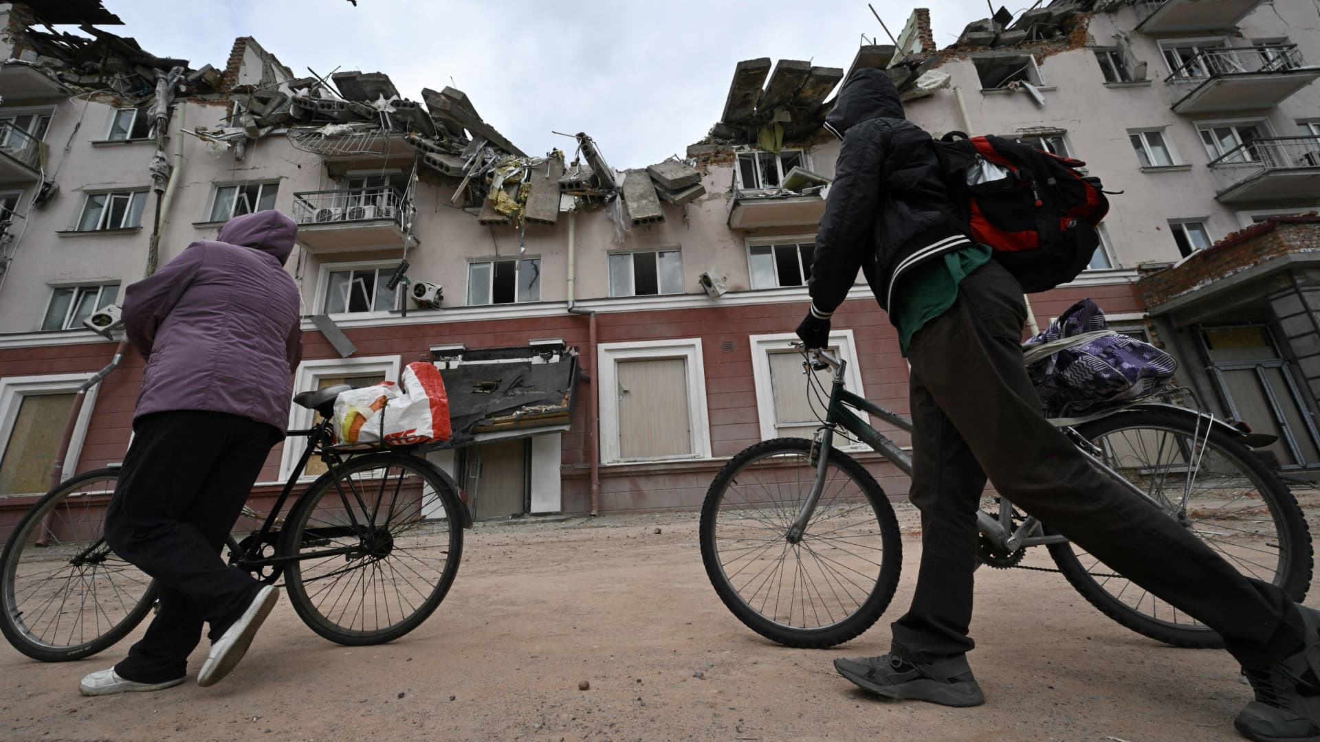 People walk past a destroyed building of the Hotel Ukraine in the northern Ukrainian city of Chernigiv on May 3, 2022, amid the Russian invasion of Ukraine. 