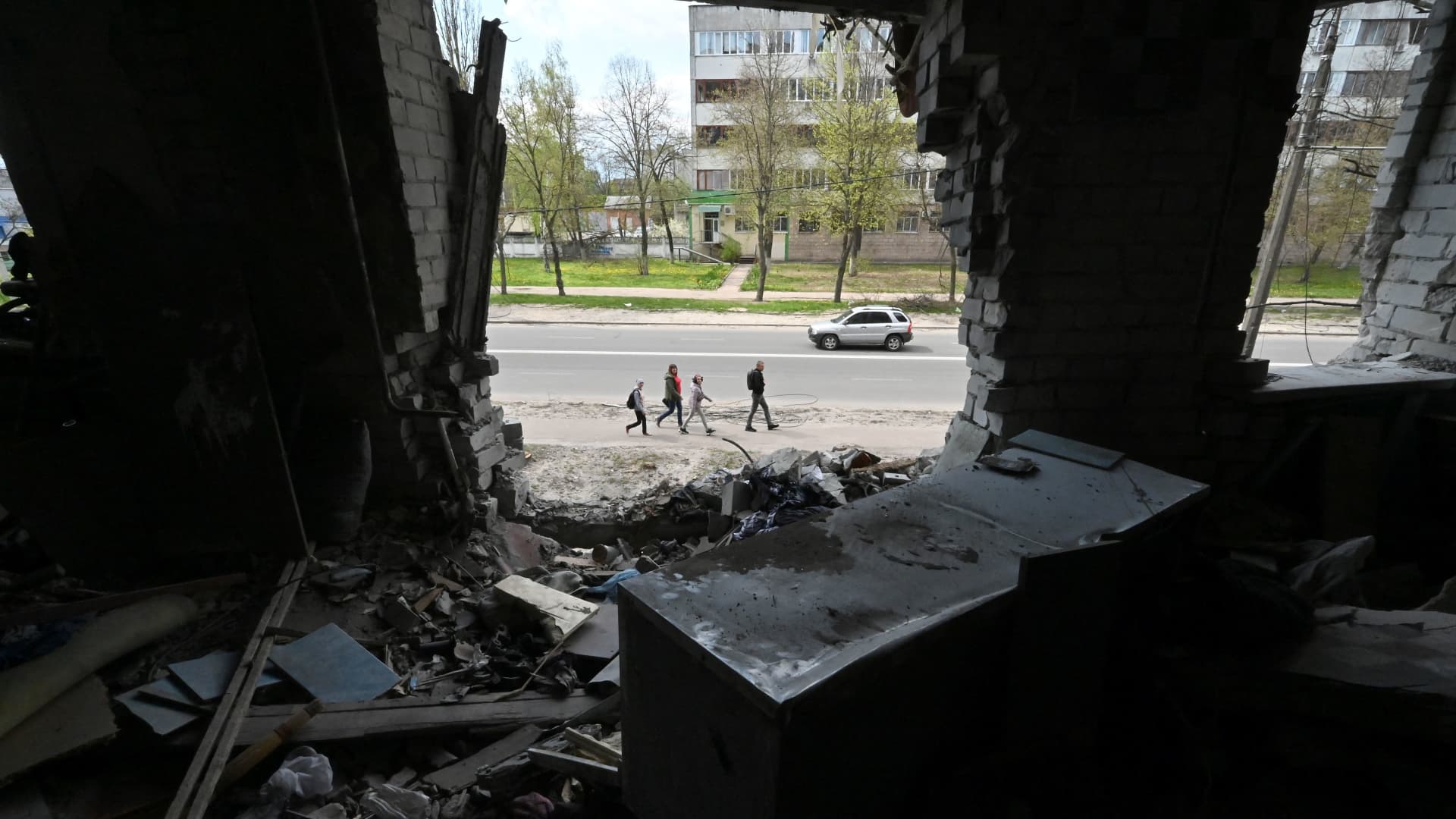 People pass by a heavily damaged residential building in the northern Ukrainian city of Chernihiv on May 3, 2022, amid the Russian invasion of Ukraine.
