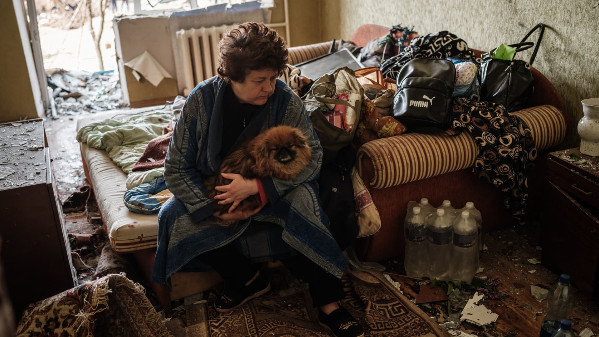 An elderly woman sits on her bed with her dog at an apartment damaged by a missile explosion in Kramatorsk, eastern Ukraine, on May 5, 2022, amid the Russian invasion of Ukraine.