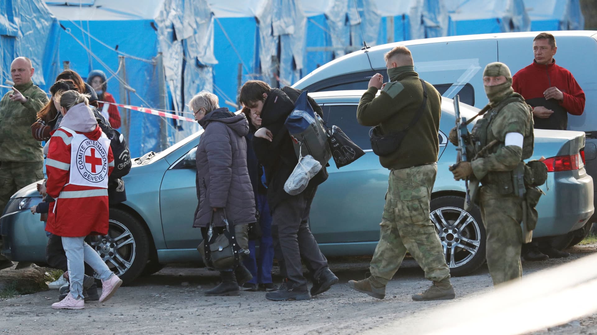 Civilians evacuated from the Azovstal steel plant in Mariupol walk accompanied by a member of the International Committee of the Red Cross (ICRC) and pro-Russian troops, as they arrive at a temporary accommodation center in the village of Bezimenne, during the Ukraine-Russia conflict in the Donetsk Region, Ukraine on May 6, 2022.