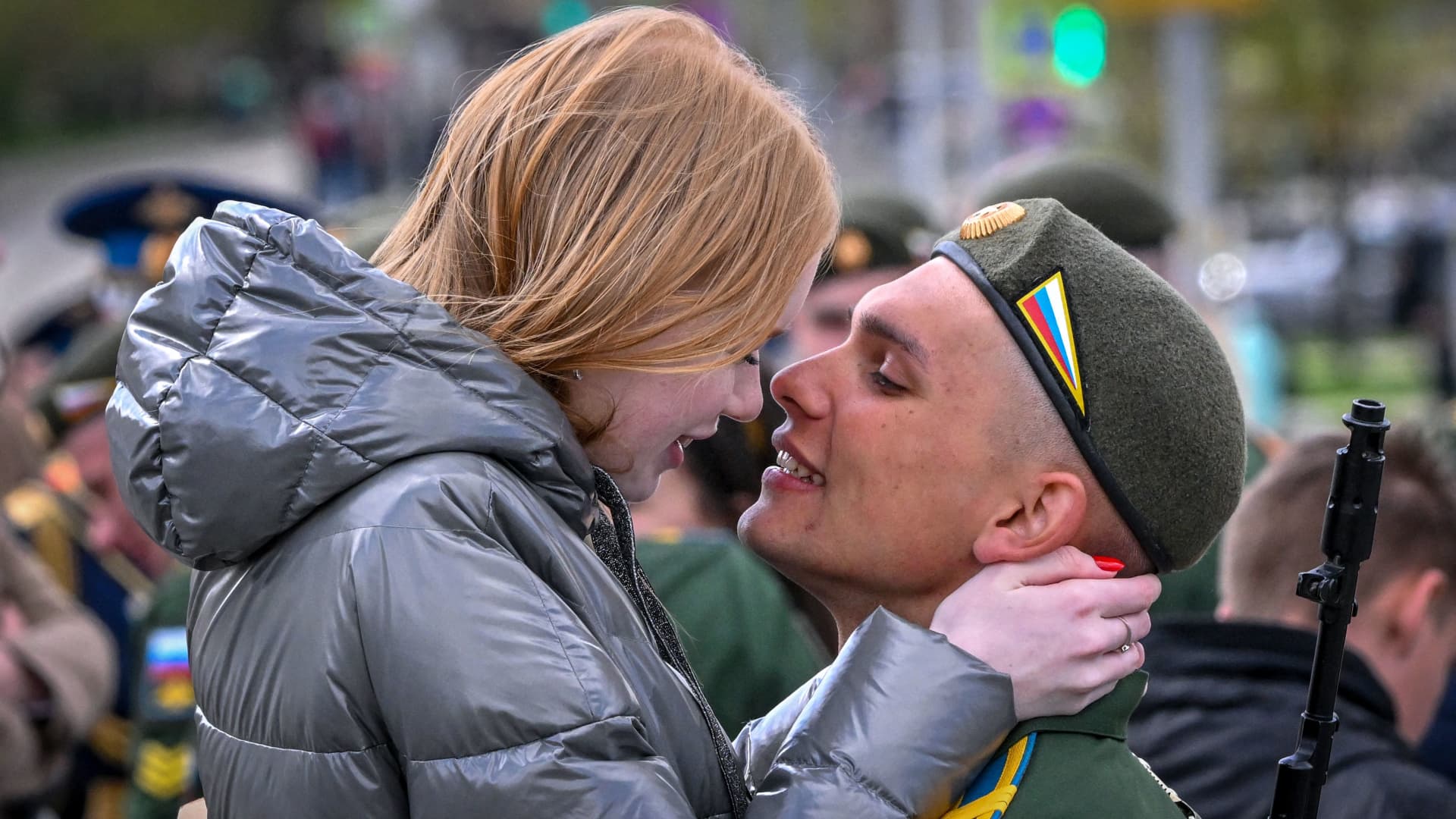 A Russian serviceman kisses his girlfriend after taking part in the Victory Day military parade in Moscow on May 9, 2022.