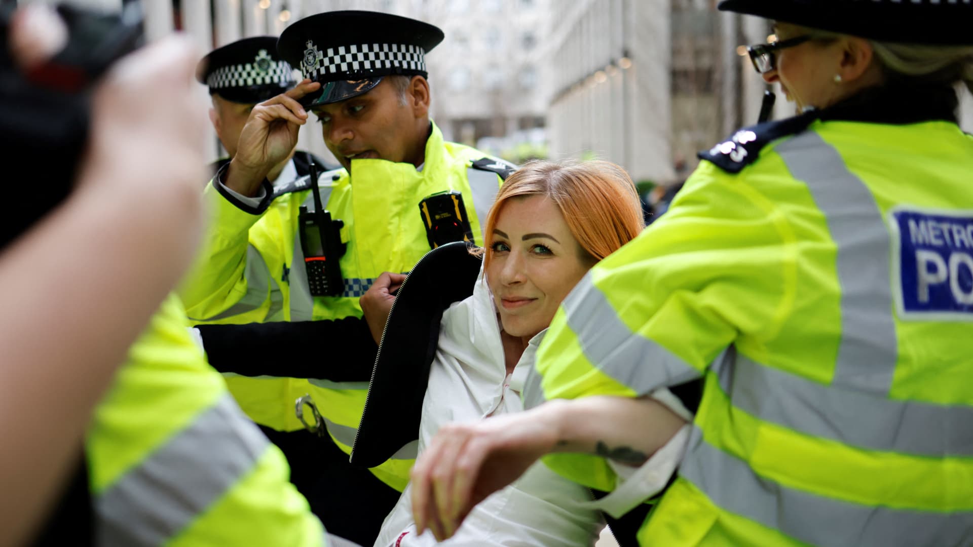 A climate activist from protest group Extinction Rebellion is carried away by police officers on April 13, 2022, after gluing her hands to the reception desk of Shell's headquarters. XR has held a series of protests in an attempt to stop the fossil fuel economy.