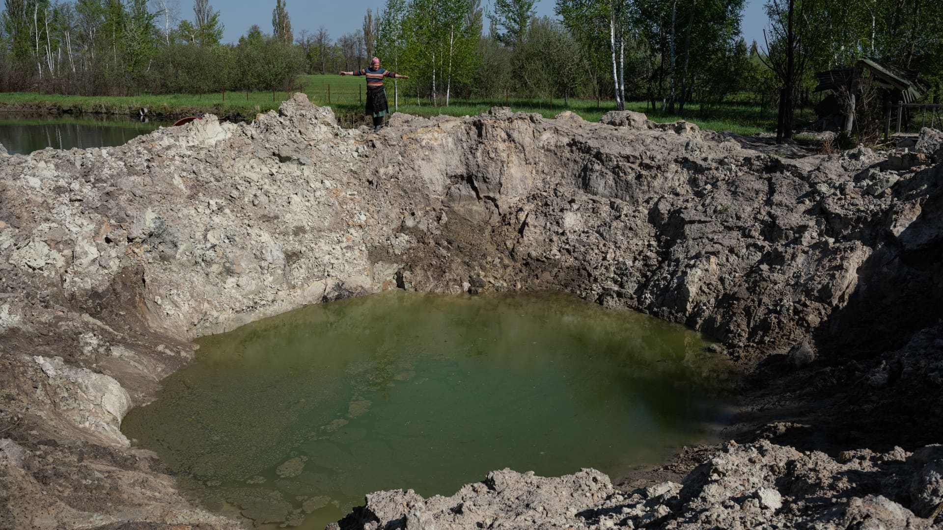 Tetiana Chernenko, 50, observes a huge crater made by an air bomb, on May 10, 2022 in Sloboda-Kukharivska, Ukraine. The towns around Kyiv are continuing a long road to what they hope is recovery, following weeks of brutal war as Russia made its failed bid to take Ukraine's capital.