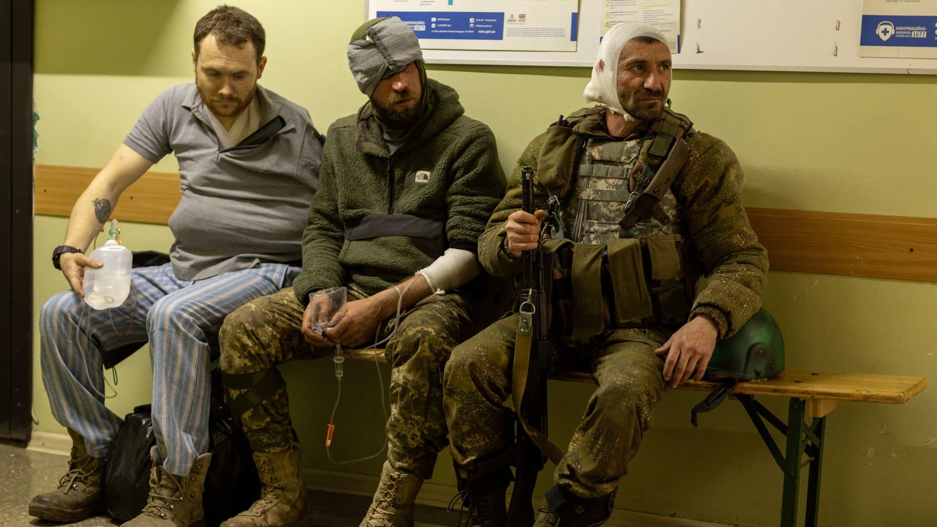 Injured Ukrainian volunteer soldiers, Maksim (C) and Andrei (R), sit on a bench in a hospital in Bakhmut, Donetsk region, Ukraine, May 5, 2022. 