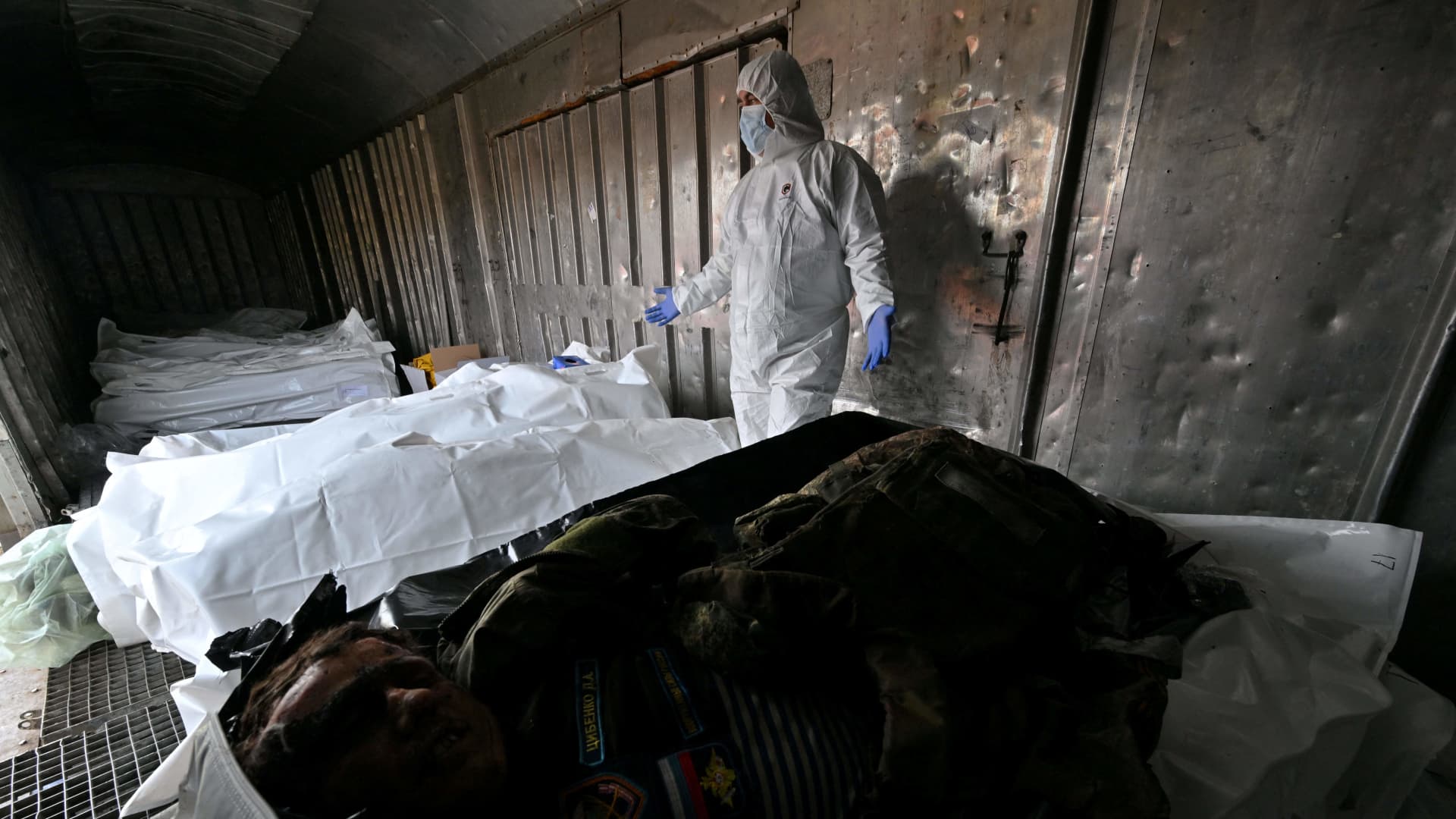 Ukrainian forensics experts examine the body of a Russian soldier exhumed in the village of Zavalivka, west of Kyiv, in a refrigerated rail car stacked with the Russian dead on May 11, 2022. 