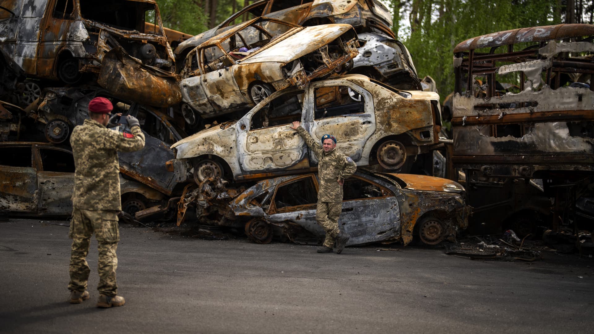 A territorial defence man poses for a photo next to cars destroyed during the Russian occupation in Irpin, on the outskirts of Kyiv, on Saturday, May 7, 2022.