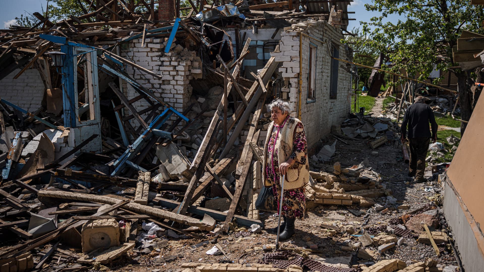 A couple brings their luggage out of their destroyed house in the village of Vilkhivka, near the eastern city of Kharkiv, on May 14, 2022, on the 80th day of the Russian invasion of Ukraine.