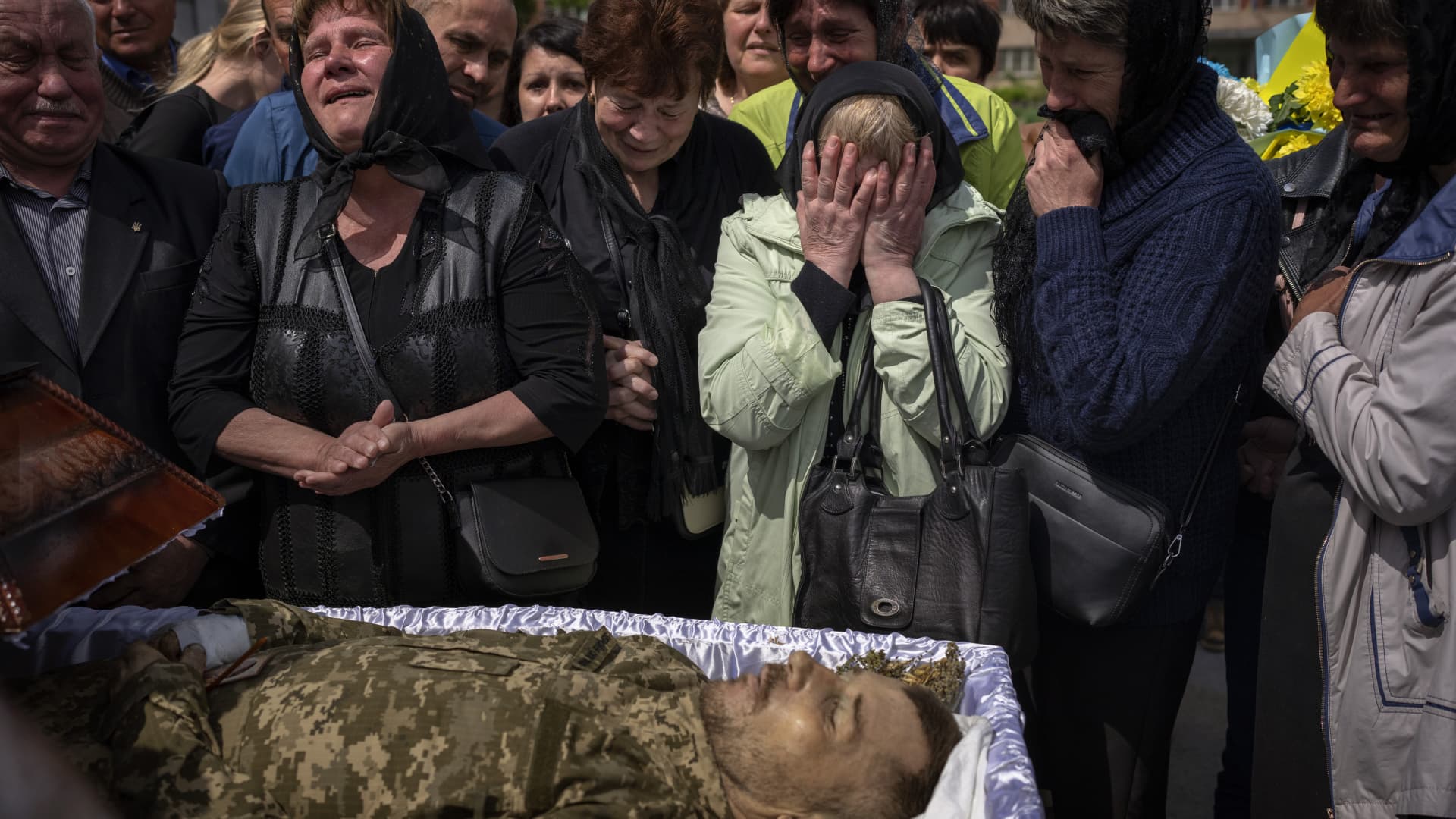 Relatives react next to the body of Pankratov Oleksandr, 49, a Ukrainian military servicemen who was killed in Donetsk province, during his funeral in Lviv, Ukraine, Saturday, May 14, 2022.
