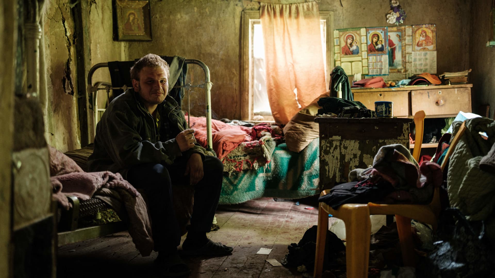 A man poses as he visits his mother in her home without electricity, water supply, and phone network in Lysychansk, eastern Ukraine, on May 15, 2022, amid the Russian invasion of Ukraine.