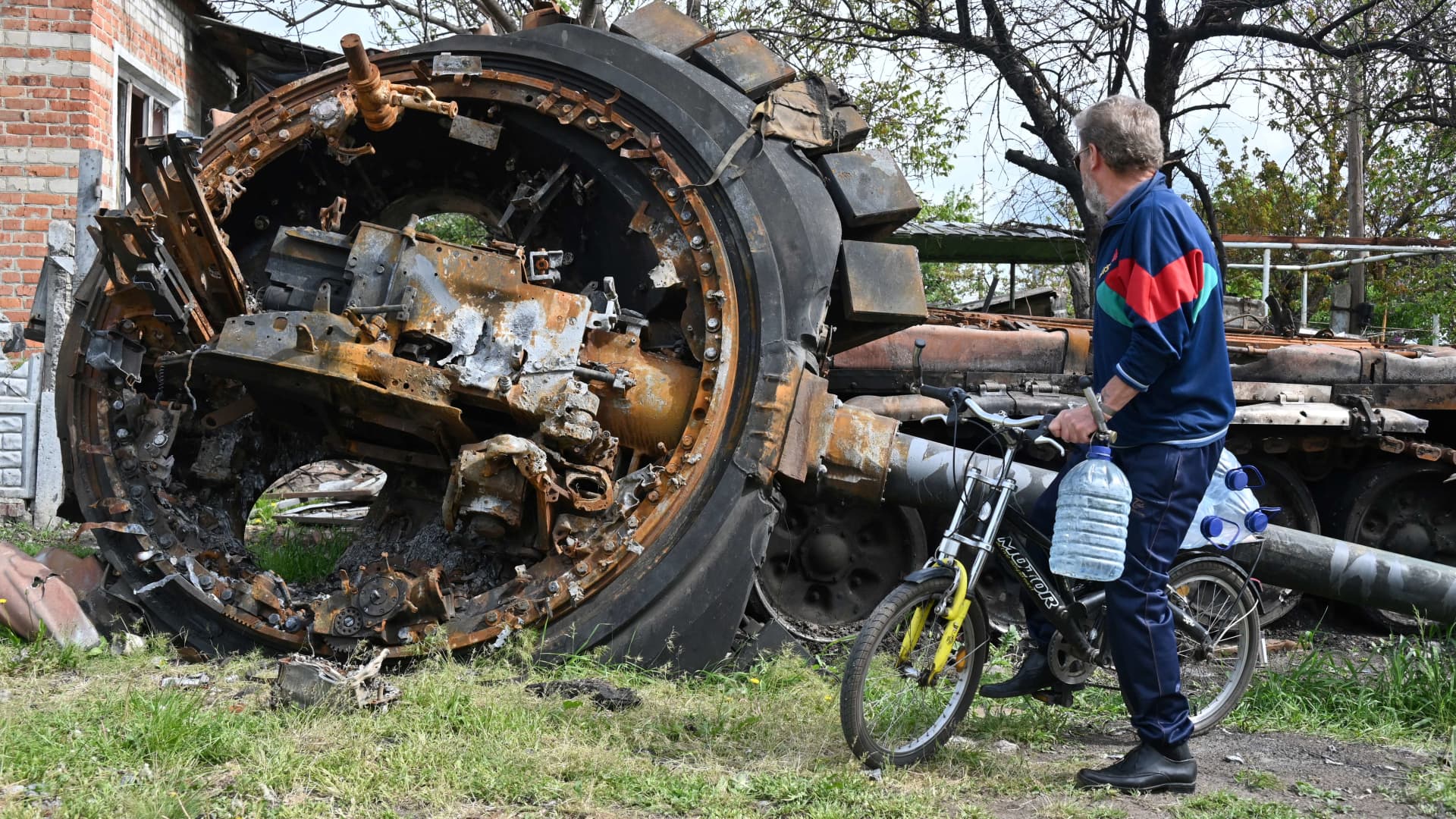 A local resident looks at a destroyed Russian tank next to a residential house in the village of Mala Rogan, east of Kharkiv, on May 15, 2022, amid Russian invasion of Ukraine.