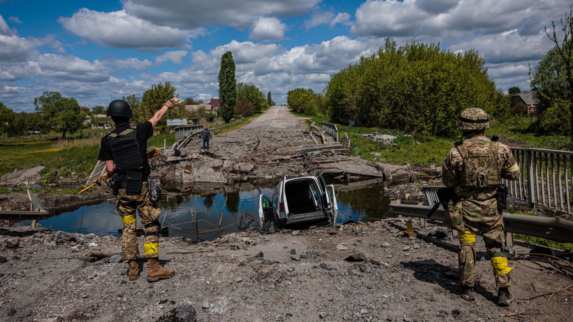 Soldiers of the Kraken Ukrainian special forces unit talk to a man at a destroyed bridge on the road near the village of Rus'ka Lozova, north of Kharkiv, on May 16, 2022.