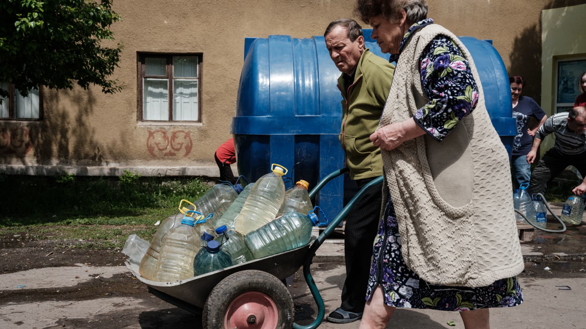 Residents carry water bottles in a wheelbarrow as they make their way from a water supply tank in Toretsk, eastern Ukraine, on May 16, 2022, on the 82nd day of the Russian invasion of Ukraine.